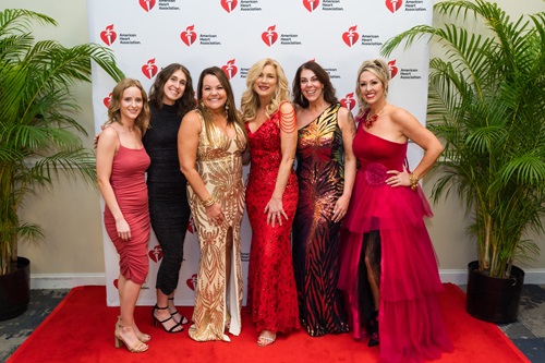Group of women in formal dress in front of American Heart Association banner.